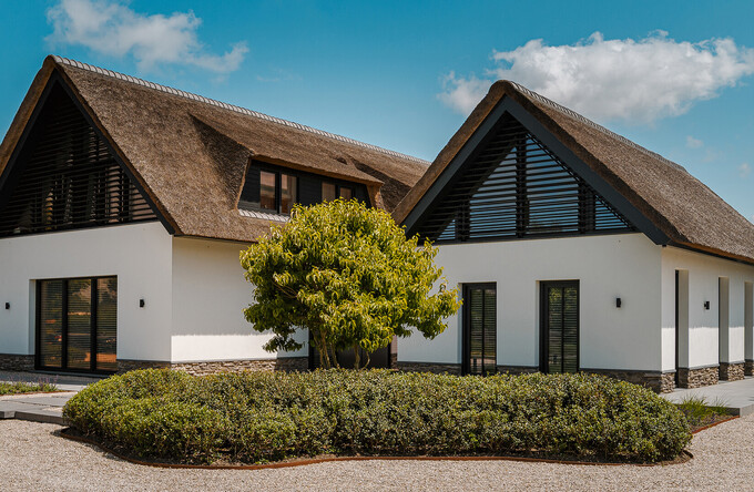 Eine weiße Villa im Polder besticht durch dunkle Lamellensysteme mit verstellbaren Lamellen